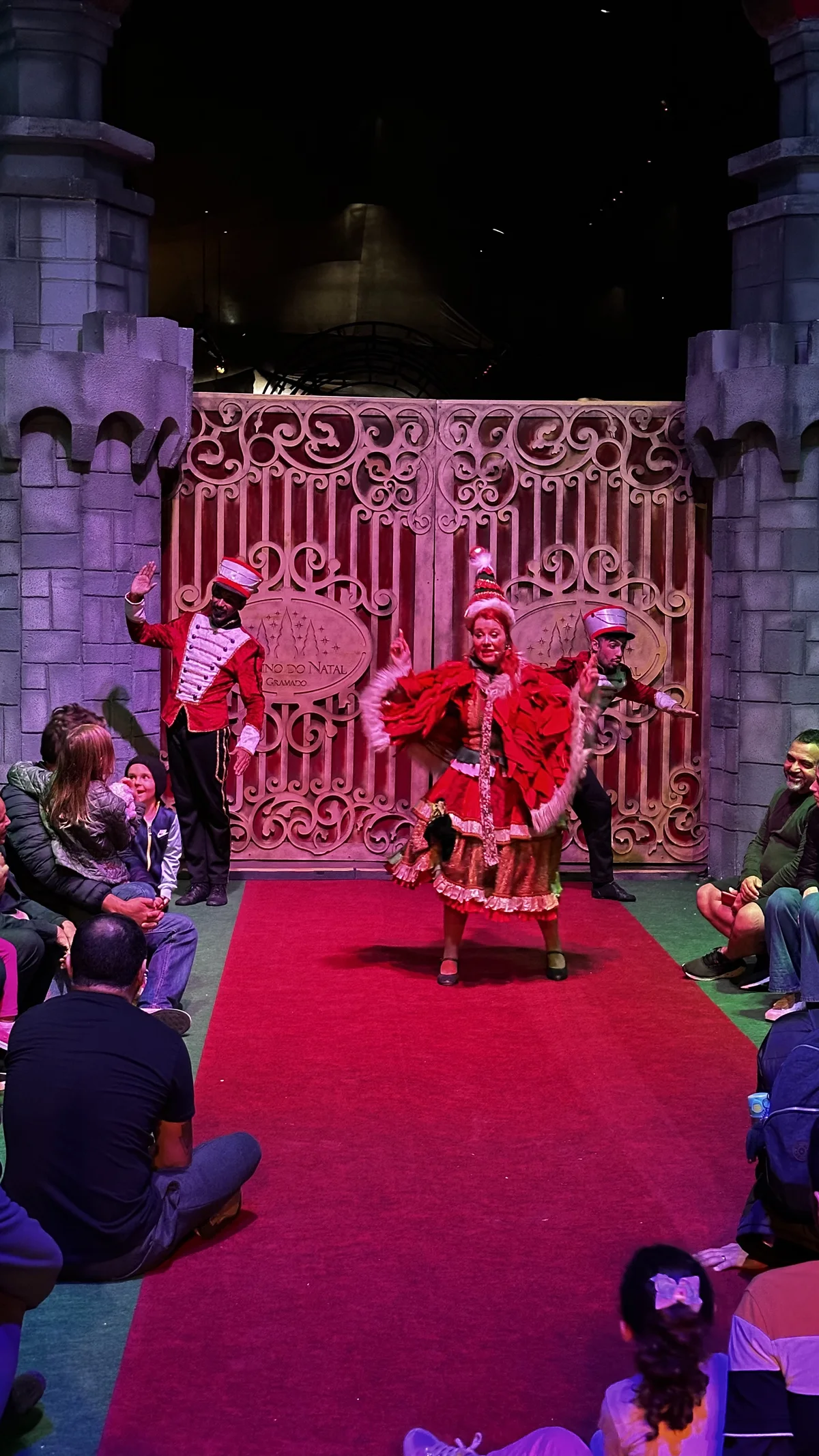 Espetáculo natalino com artistas diante de um grande portal iluminado